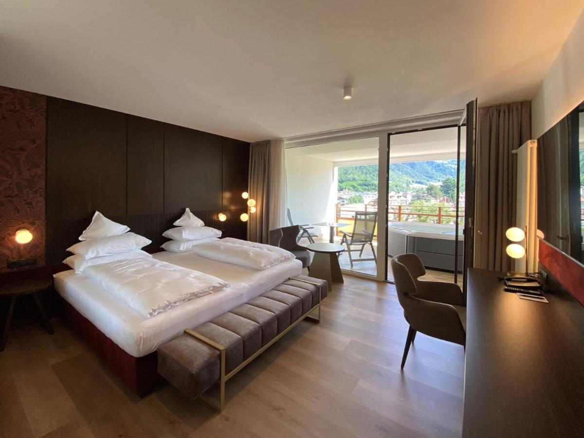 een slaapkamer met een groot bed en een balkon bij Dominik Alpine City Wellness Hotel Brixen - Adults only in Bressanone
