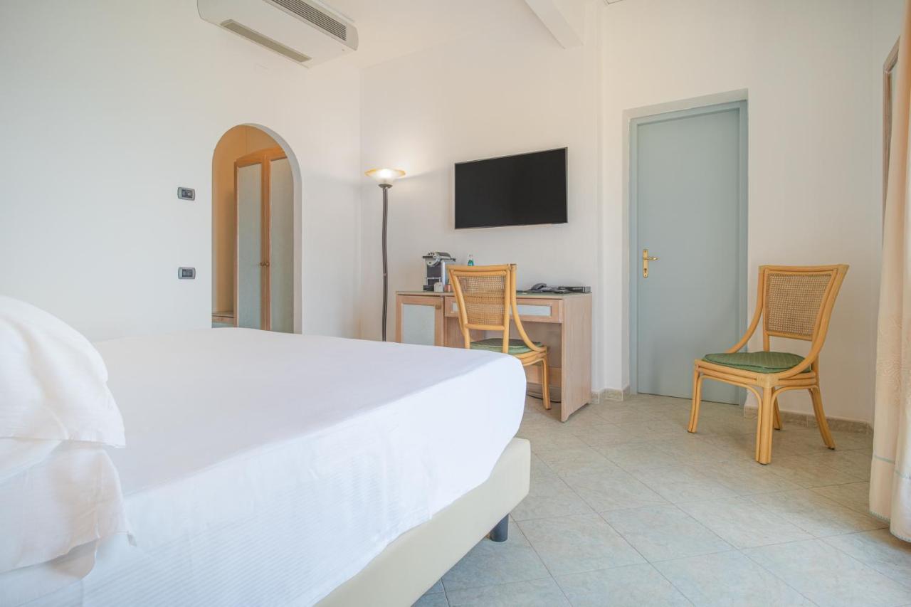 een slaapkamer met een bed, een bureau en stoelen bij Felix Hotels - Hotel La Baja in Santa Caterina