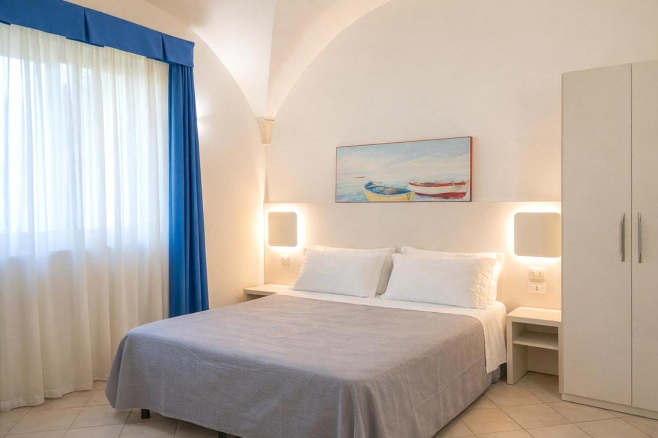 een witte slaapkamer met een bed en een raam bij Color Dolmen Family Village in Minervino di Lecce +5 foto's