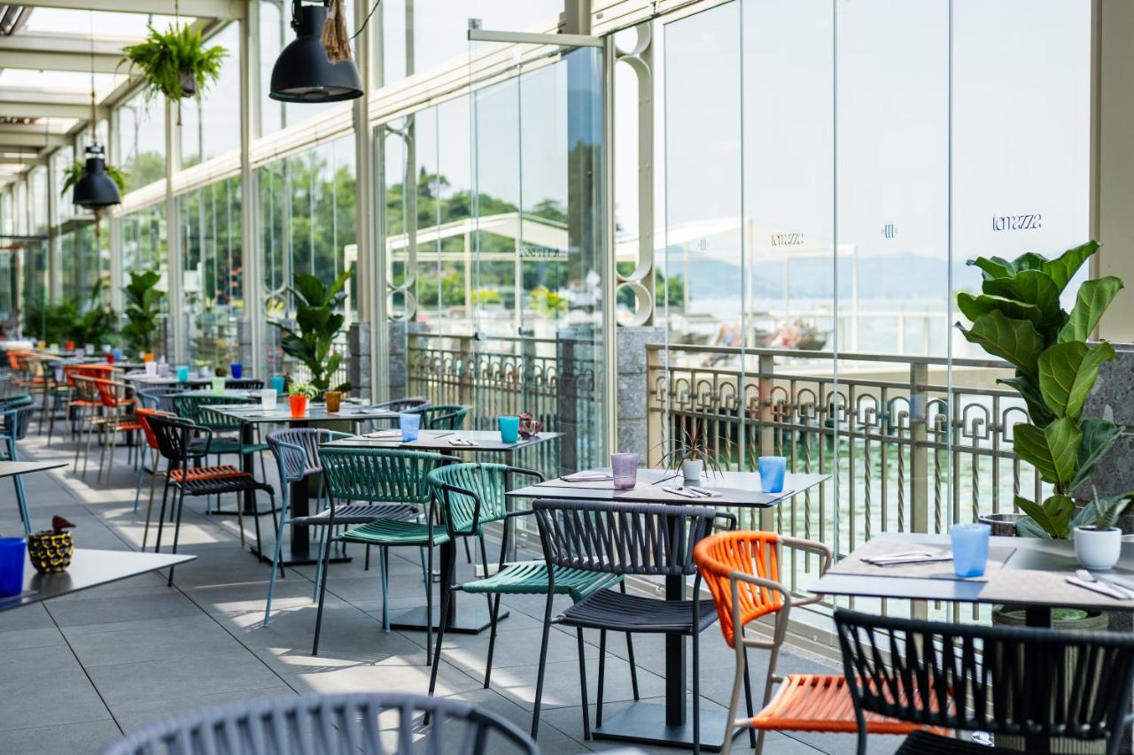 een restaurant met tafels, stoelen en ramen bij Araba Fenice Hotel in Iseo