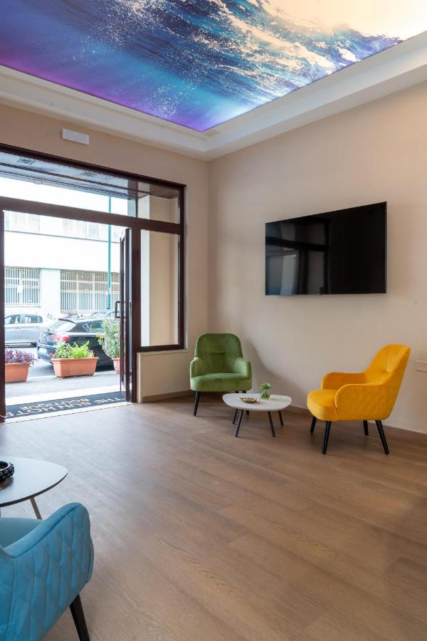 een woonkamer met een tv, een bank en stoelen bij THE SUN HOTEL BOUTIQUE NAPOLI in Napels