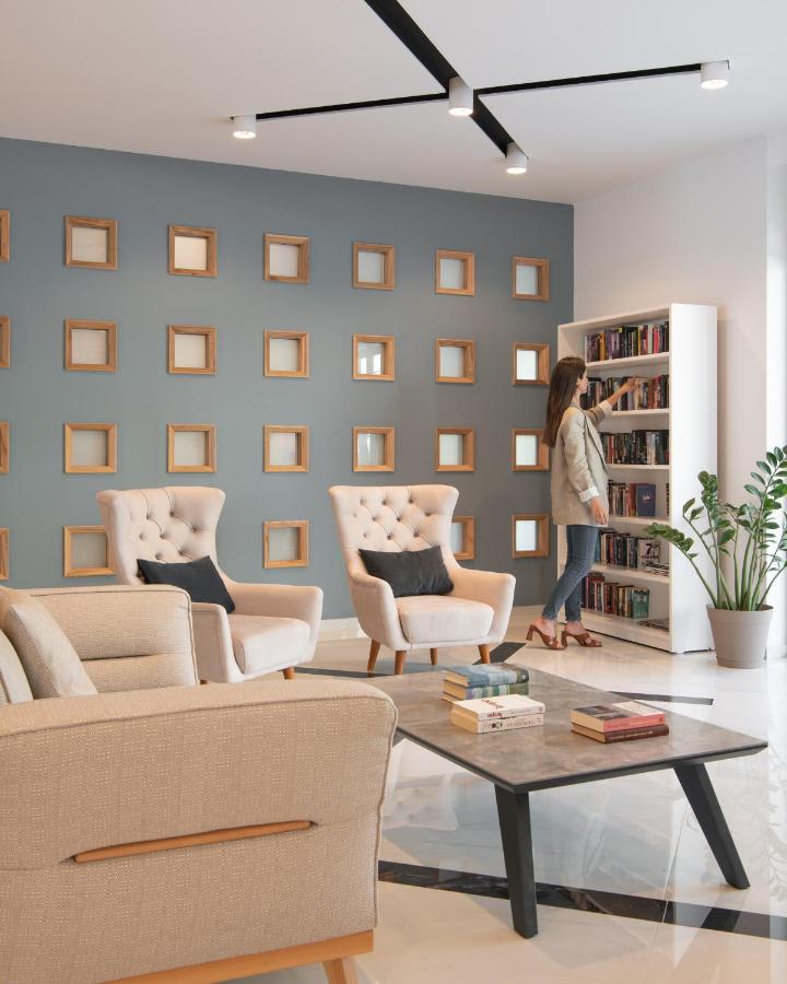 Een vrouw staat in een woonkamer met een boekenplank. bij Bio Suites Hotel & Spa in Rethimnon