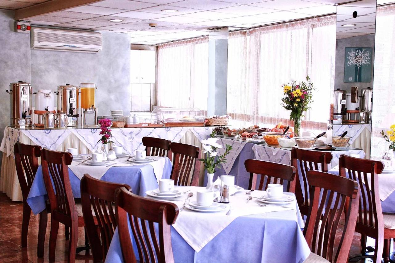 een restaurant met tafels en stoelen met witte tafelkleden bij Apollo Hotel in Athene