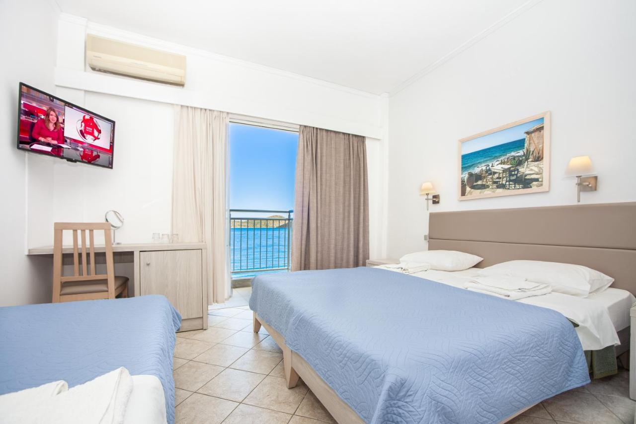 een hotelkamer met twee bedden, een bureau en een raam bij Aristea Hotel in Elounda