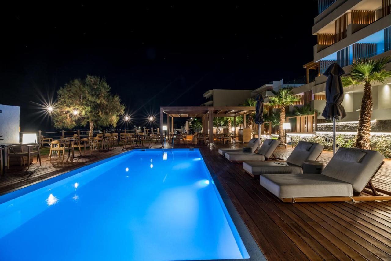 een zwembad 's nachts met ligstoelen en tafels bij AKASHA Beach Hotel & Spa in Chersonissos