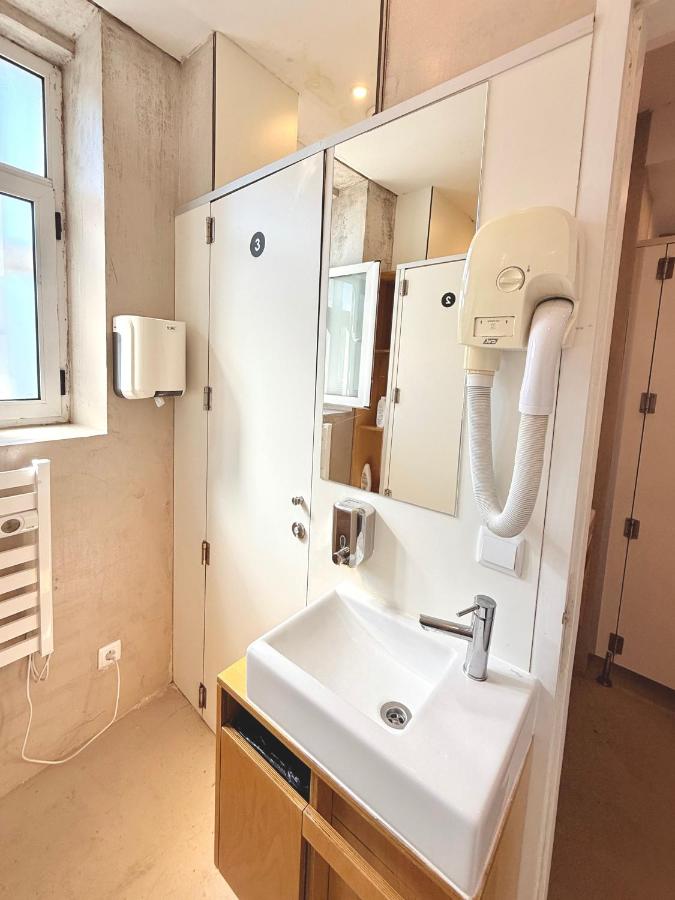 een badkamer met een wastafel en een spiegel bij Rivoli Cinema Hostel in Porto