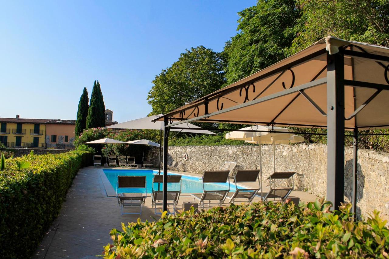 een terras met een tafel en stoelen onder een parasol bij AHG Donna Silvia Wellness Hotel in Manerba del Garda