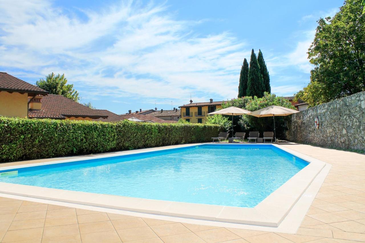 een zwembad in een tuin naast een hek bij AHG Donna Silvia Wellness Hotel in Manerba del Garda