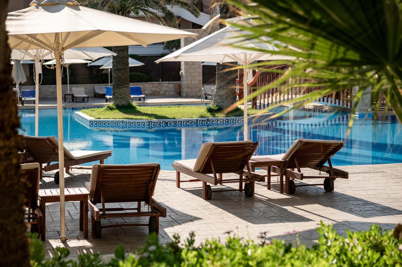 een groep stoelen en parasols naast een zwembad bij Caldera Creta Paradise in Plataniás
