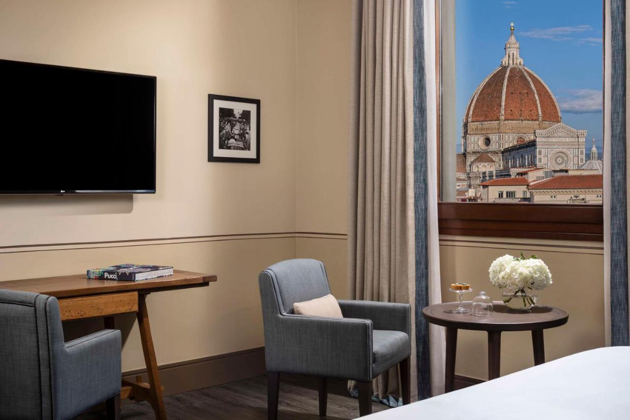 een hotelkamer met een bureau, stoelen en een televisie bij Tivoli Palazzo Gaddi Firenze Hotel in Florence
