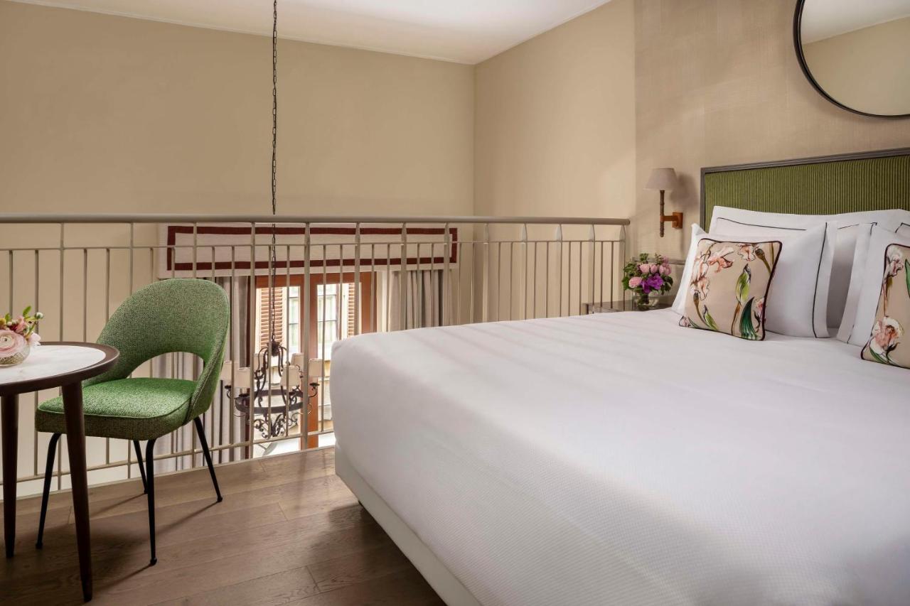 een slaapkamer met een groot wit bed en een tafel bij Tivoli Palazzo Gaddi Firenze Hotel in Florence