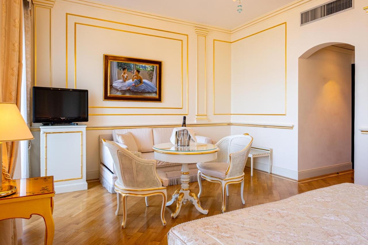 een woonkamer met een tafel en een bank bij Hotel Astoria in Stresa