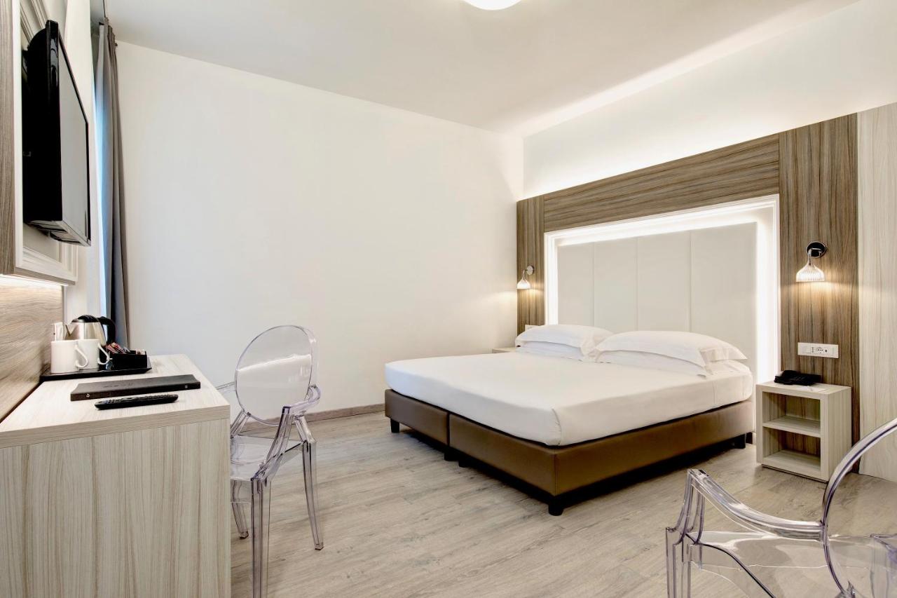 een slaapkamer met een bed, een tv en stoelen bij Hotel San Giusto in Trieste