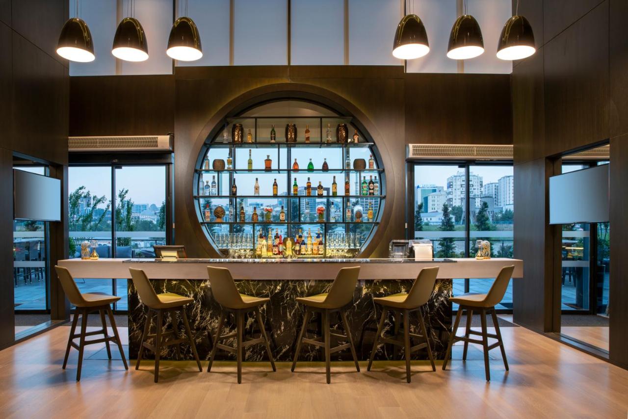 een bar met stoelen en een tafel in een kamer met ramen bij Centro Westside by Rotana in Istanbul
