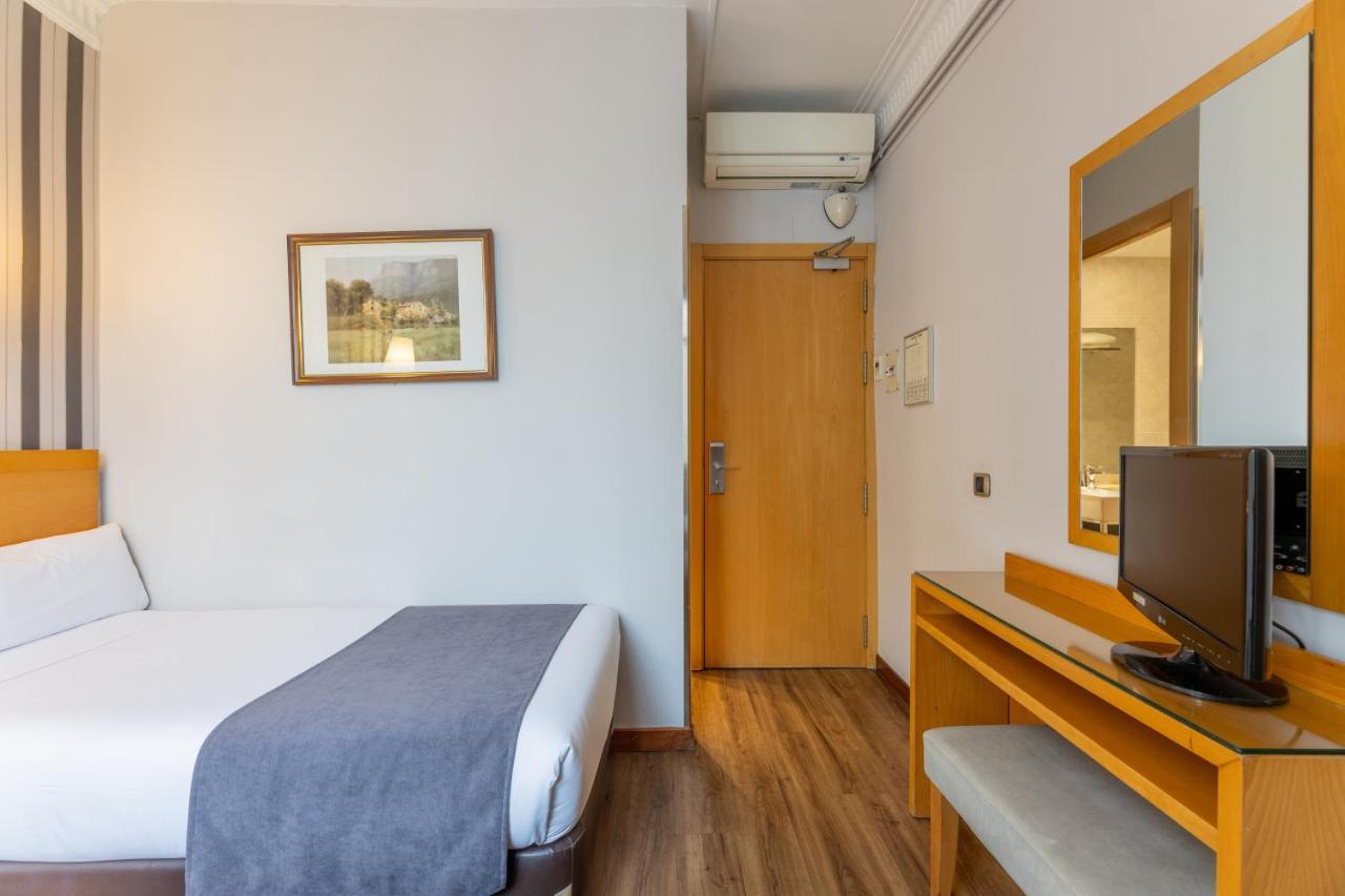 een hotelkamer met een bed en een televisie bij Hotel Lyon in Barcelona
