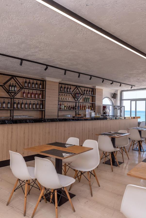 een restaurant met houten tafels en witte stoelen bij Azure Mare Hotel in Chersonissos