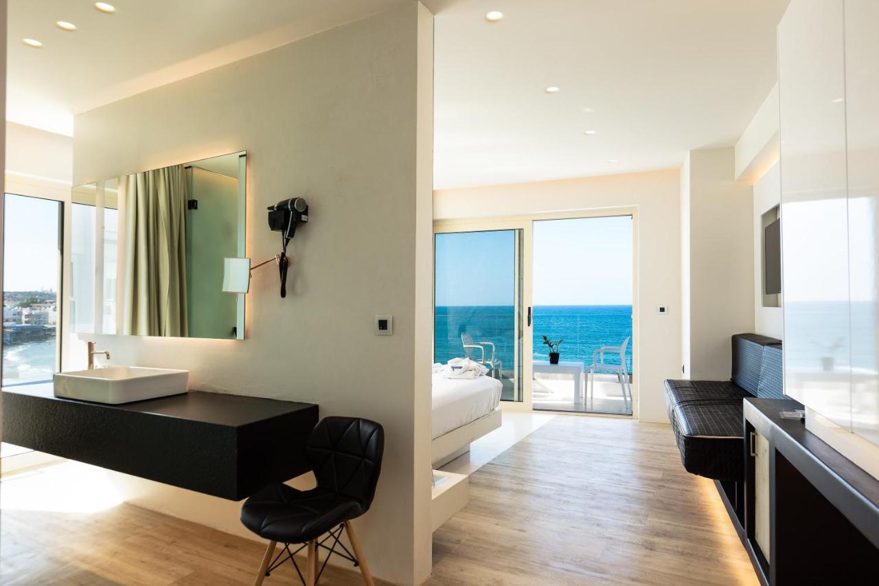 een badkamer met een wastafel en een bureau met een spiegel bij Kahlua Sea View Suites - Adults Only in Chersonissos