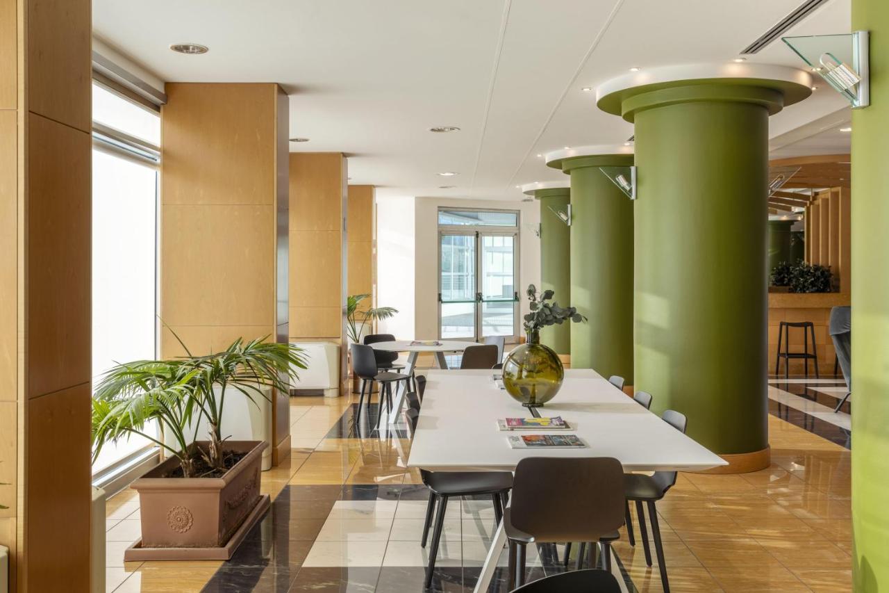 een kantoor met groene zuilen, tafels en stoelen bij B&B HOTEL Cuneo Cristal in Cuneo