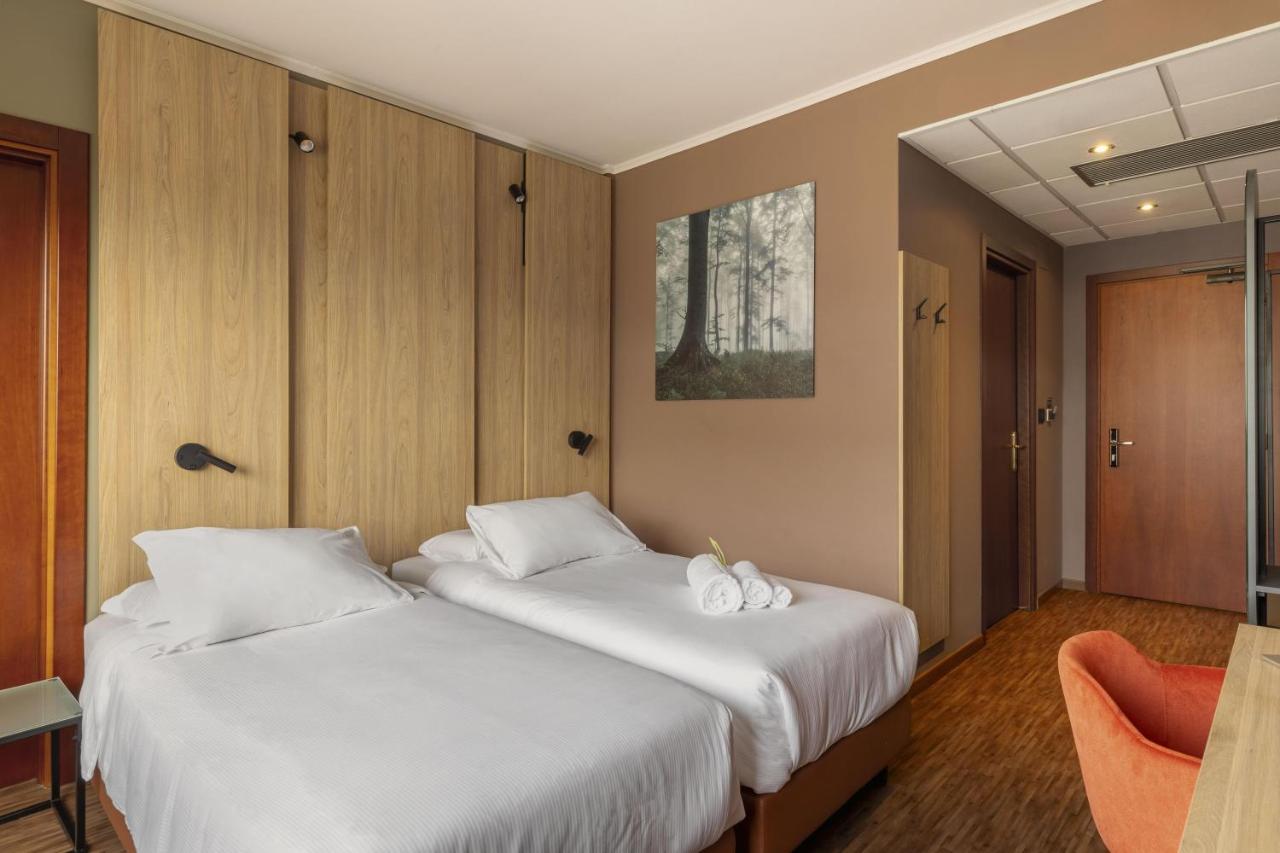 Twee bedden in een hotelkamer met witte lakens. bij B&B HOTEL Cuneo Cristal in Cuneo