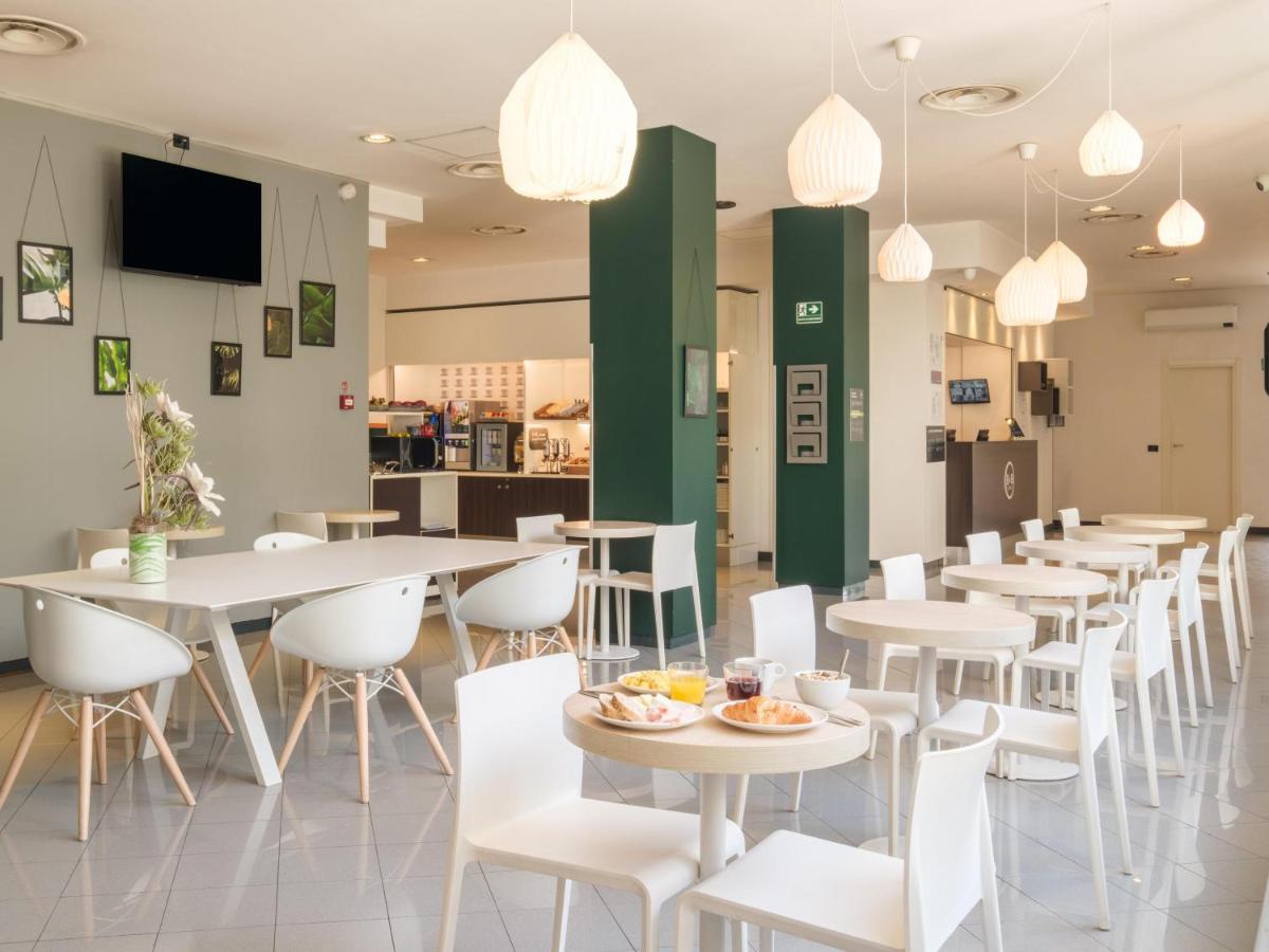 een restaurant met witte tafels en witte stoelen bij B&B Hotel Faenza in Faenza
