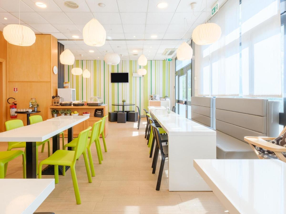 een restaurant met witte tafels en groene stoelen bij B&B Hotel Ravenna in Ravenna
