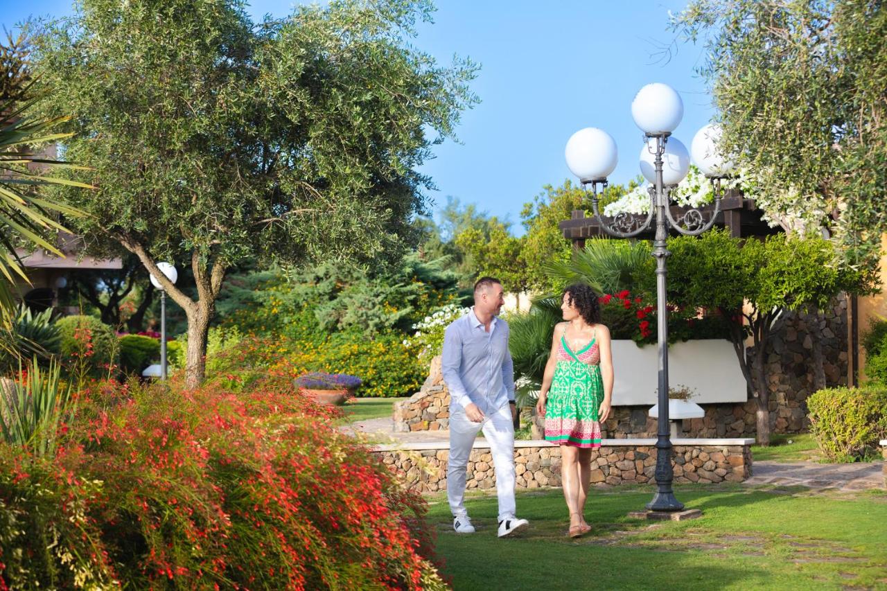 een man en een vrouw staan in een tuin bij Hotel Baia di Nora in Pula