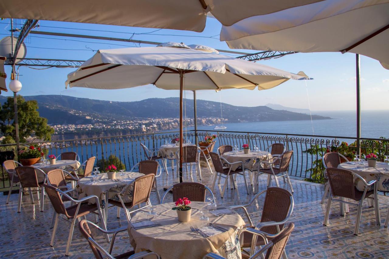 een restaurant met tafels en stoelen met uitzicht op de oceaan bij Baia Serena in Vico Equense