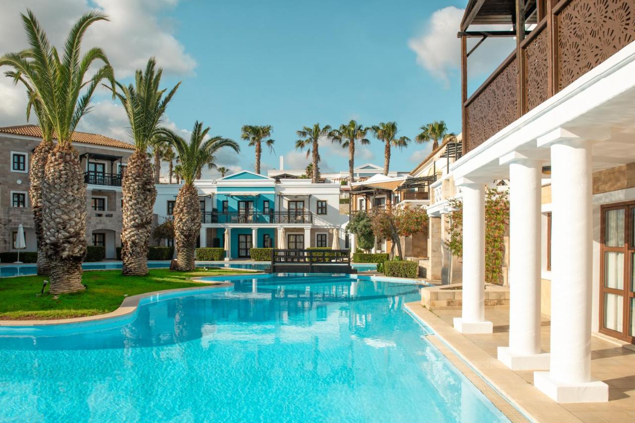 een groot zwembad voor een huis met palmbomen bij Mitsis Royal Mare in Chersonissos