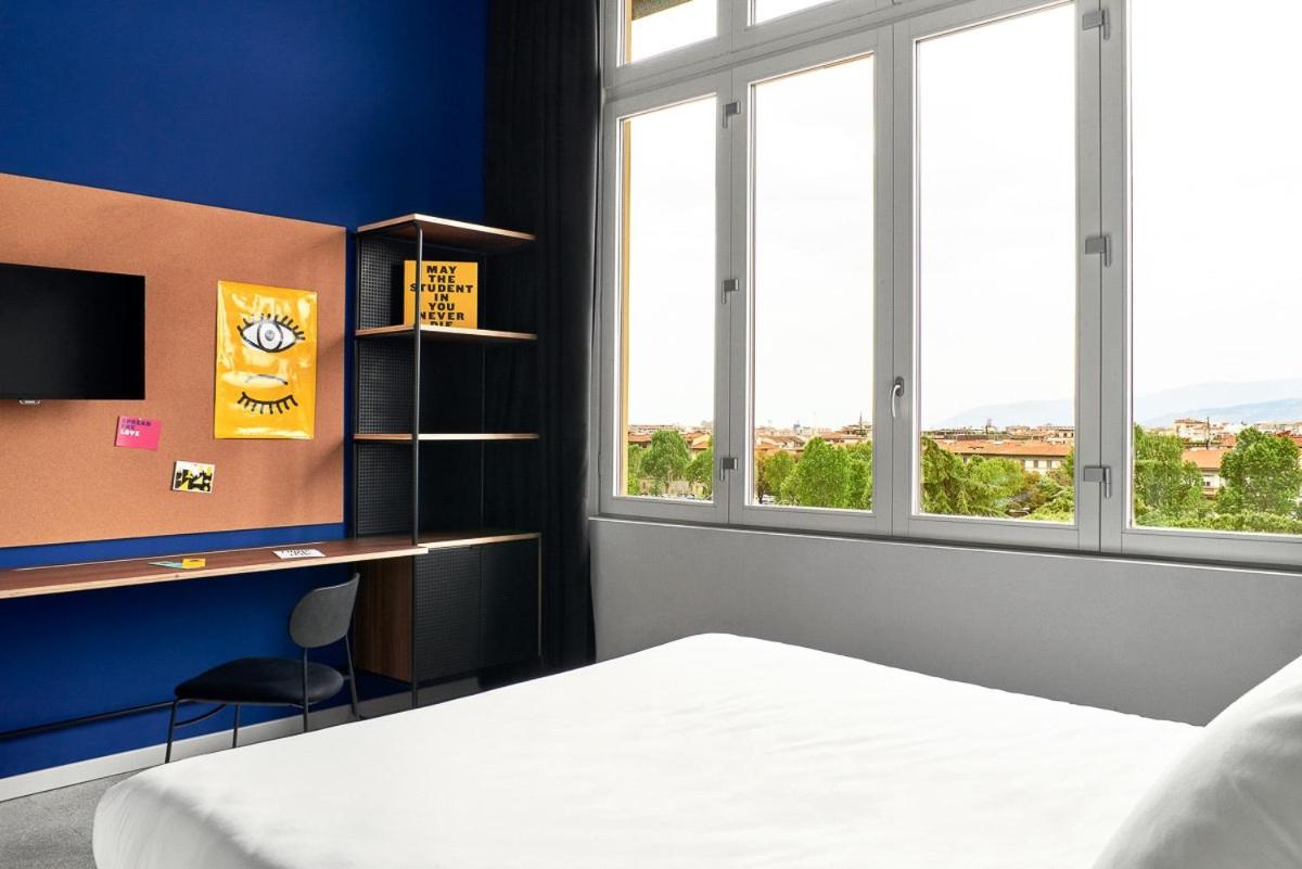 een slaapkamer met een bed, een bureau en ramen bij The Social Hub Florence Lavagnini in Florence