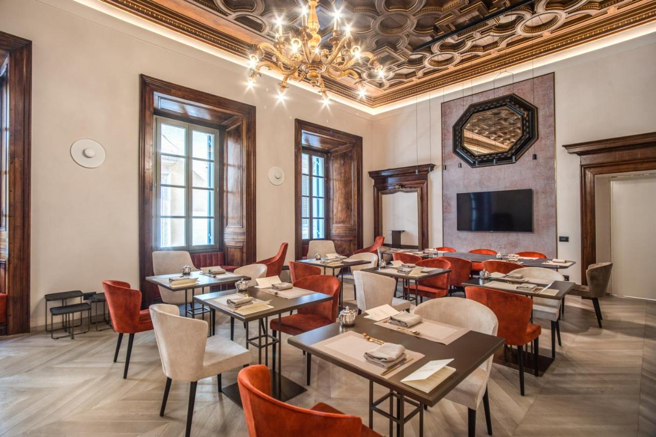 een restaurant met tafels en stoelen en een kroonluchter bij Martius Private Suites Hotel in Rome