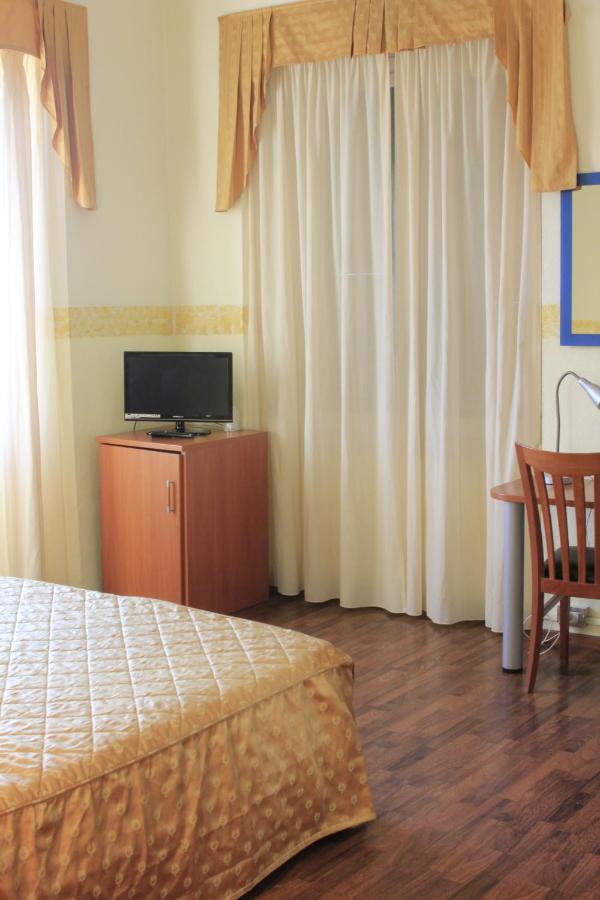 een slaapkamer met een bed, een tv en gordijnen bij Hotel Bellevue in Genua