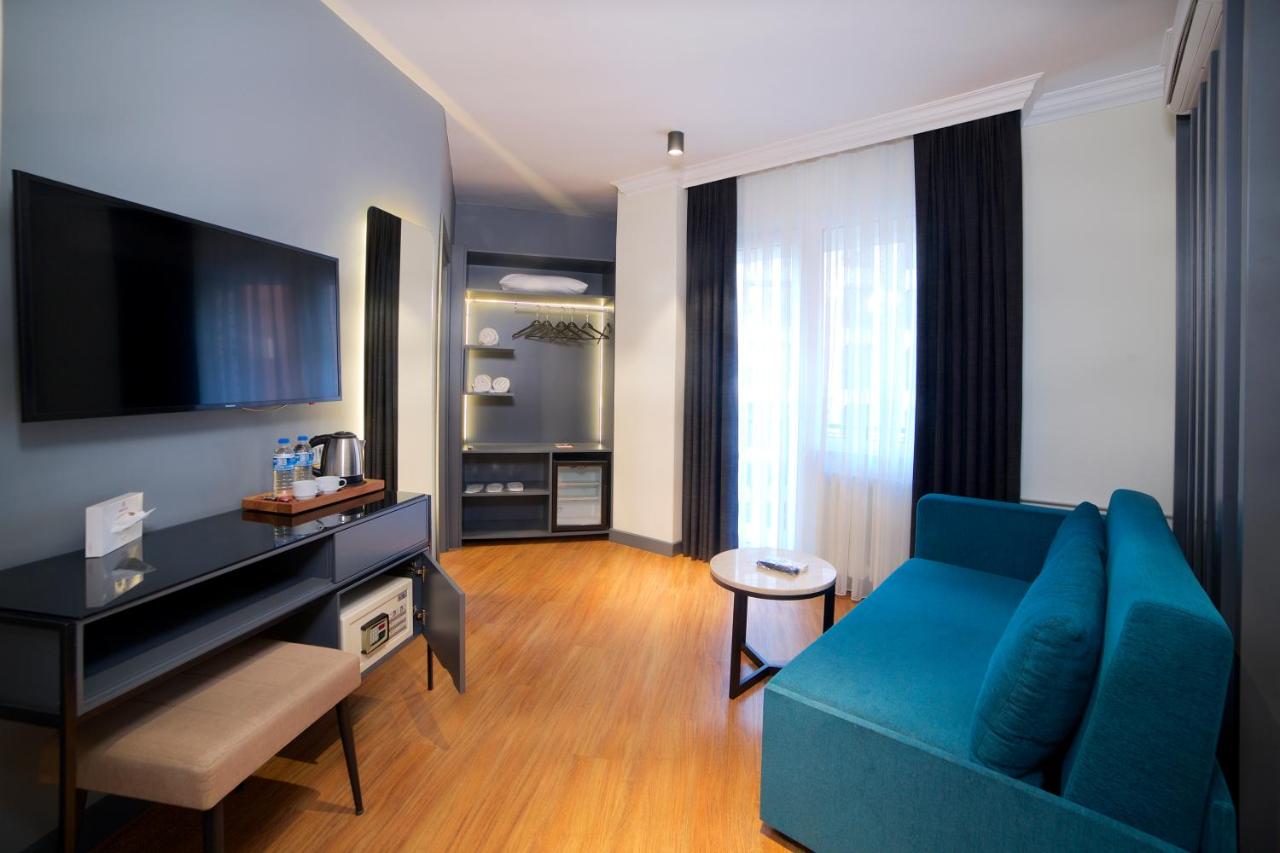 een woonkamer met een blauwe bank en een televisie bij Barin Hotel in Istanbul