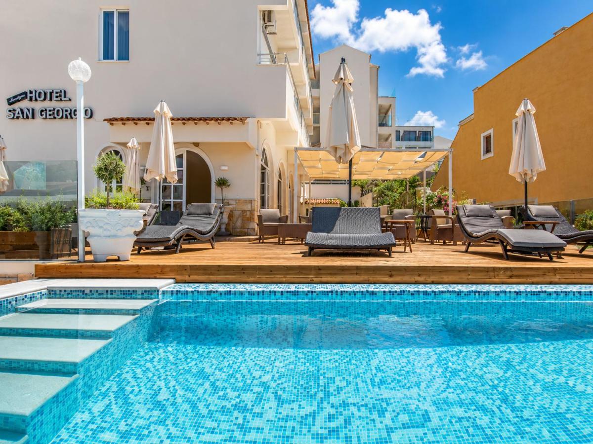 een zwembad met stoelen en parasols naast een gebouw bij San Georgio Hotel in Agios Georgios Pagon