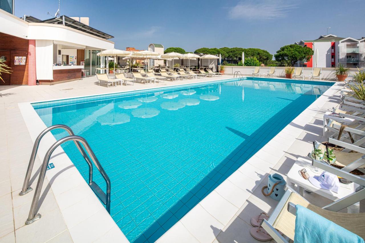 een zwembad bij een hotel met ligstoelen en parasols bij Hotel Jasminum in Bibione