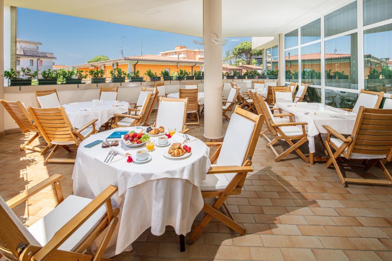 een restaurant met tafels en stoelen waarop eten staat bij Hotel Jasminum in Bibione