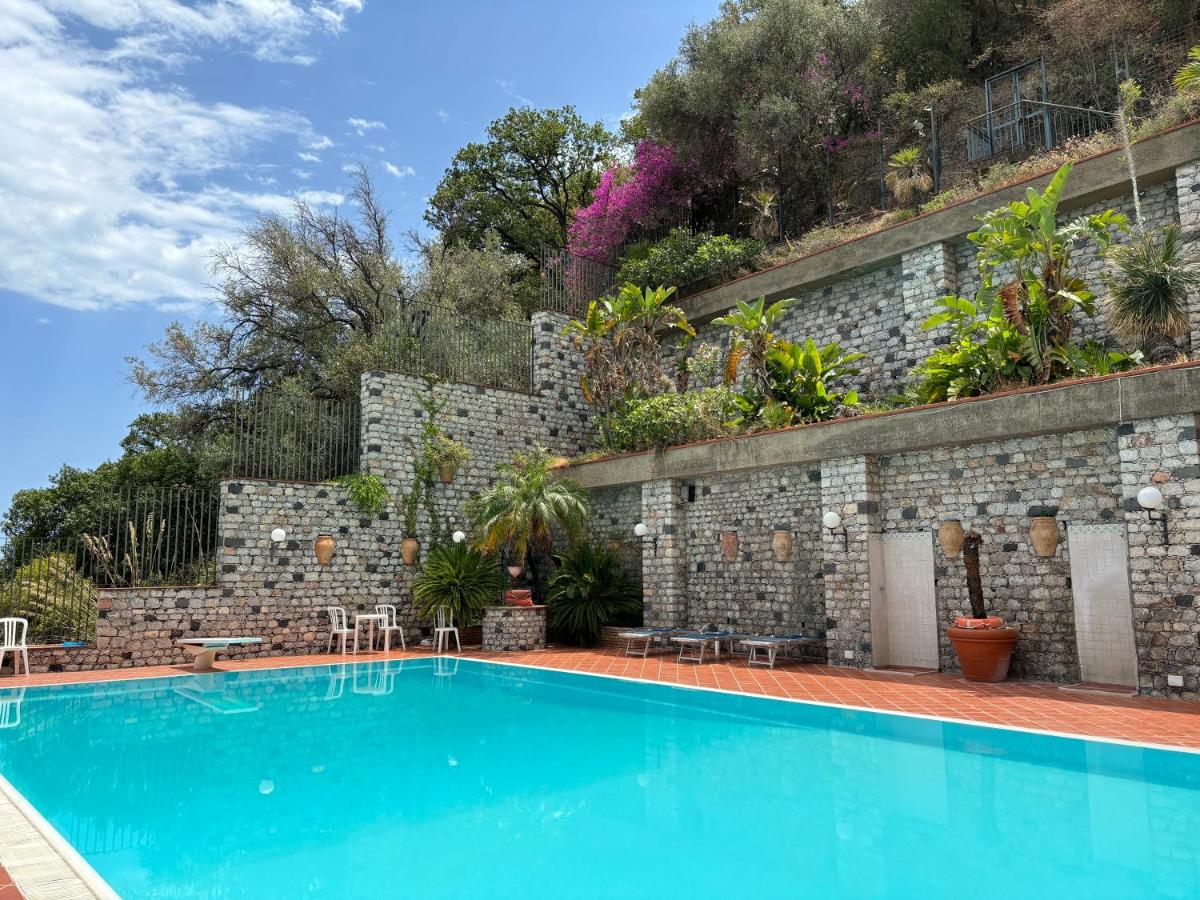 een zwembad voor een bakstenen muur met een blauw zwembad bij Bay Palace Mazzarò in Taormina