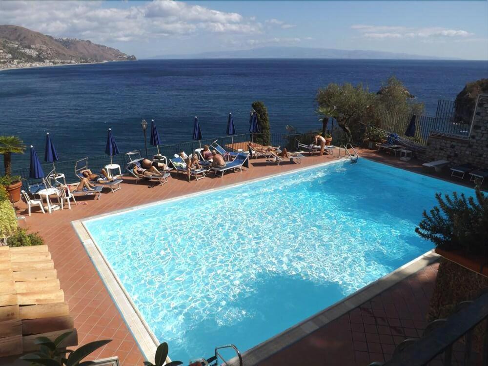 een zwembad met uitzicht op de oceaan bij Bay Palace Mazzarò in Taormina