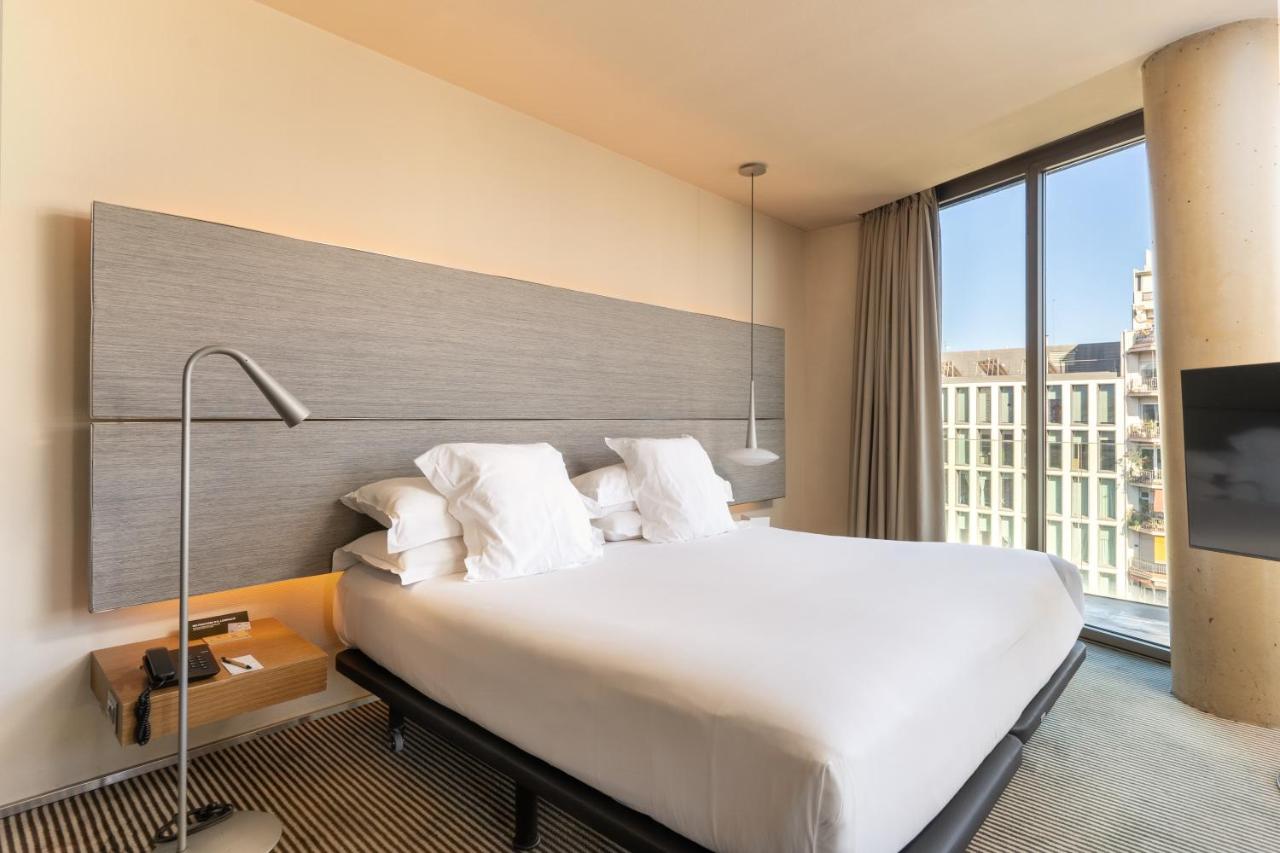 een hotelkamer met een groot bed en een groot raam bij B Hotel in Barcelona