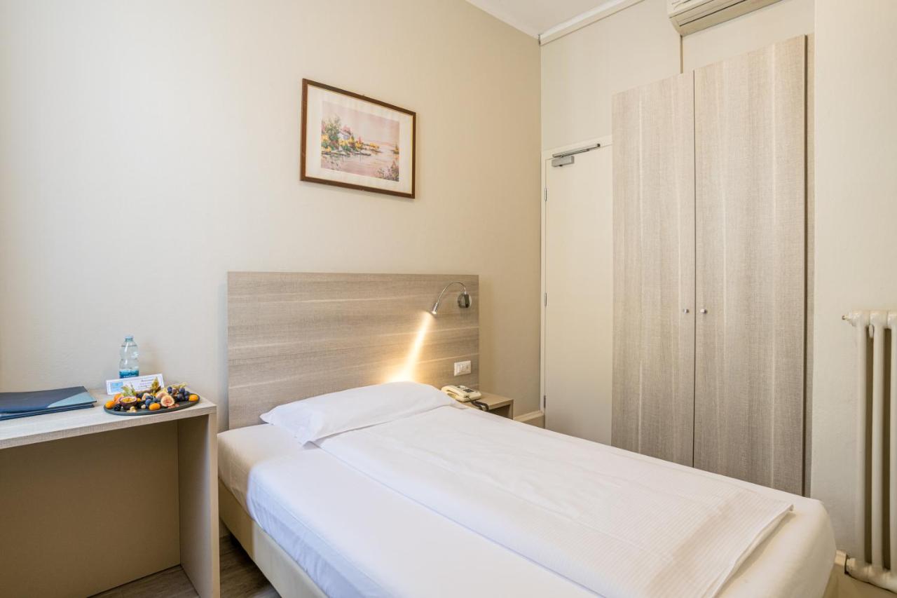 een kleine slaapkamer met een bed en een bureau bij Hotel Bazzoni in Tremezzo