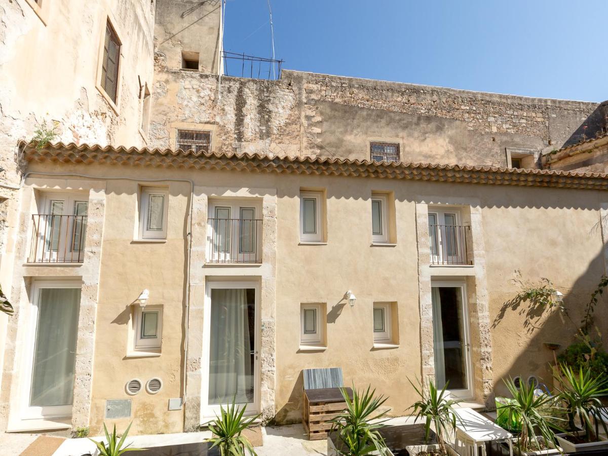 een oud stenen gebouw met ramen en planten bij Residence Ortigia in Siracusa