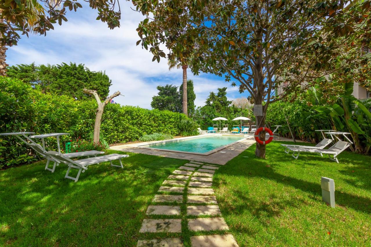 een zwembad met twee banken in een tuin bij Relais Regina Rosanna in Gallipoli