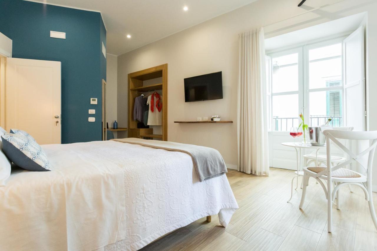 een slaapkamer met een wit bed en een blauwe muur bij Bellaroto Suite & Spa - Charming Boutique Rooms in Palermo