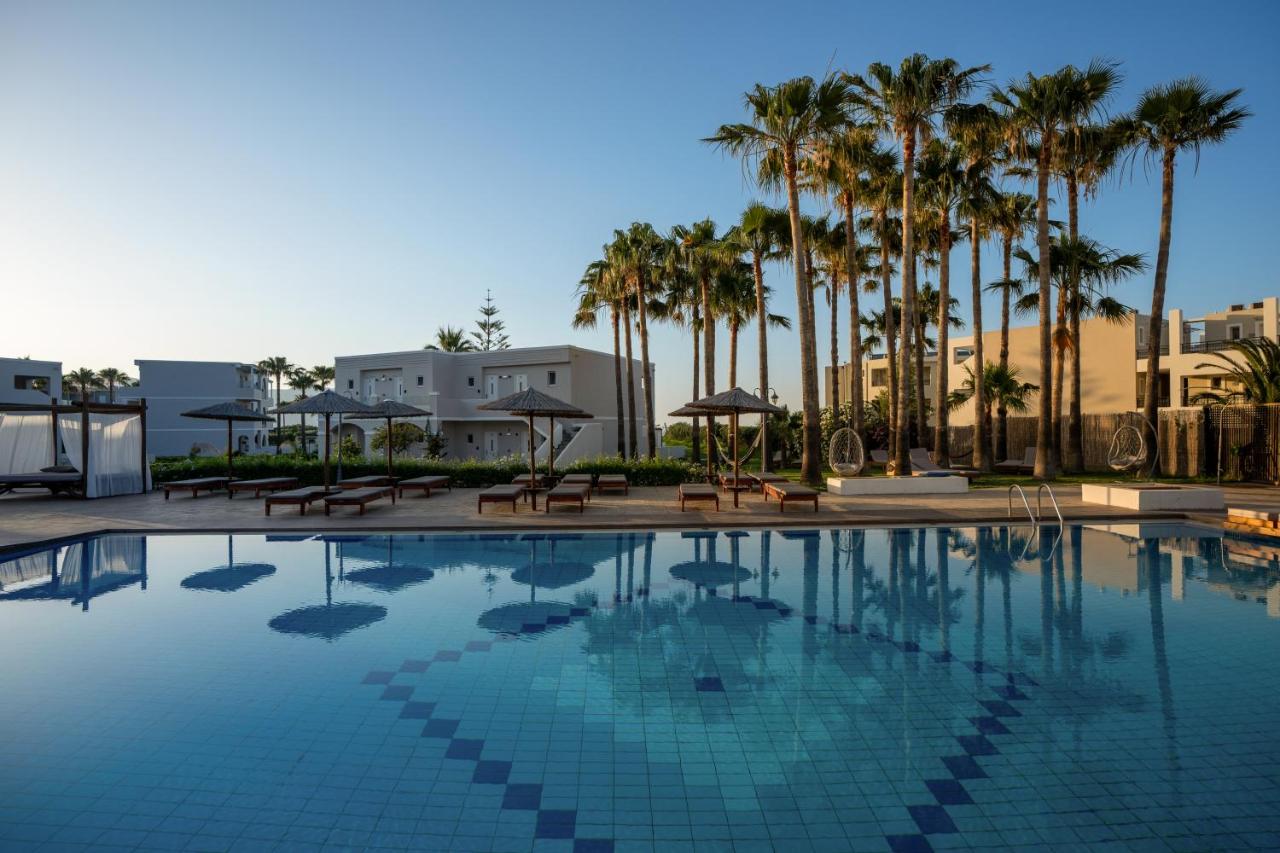 een groot zwembad met palmbomen en parasols bij Delfina Tropic Beach - Adults Only in Georgioupolis