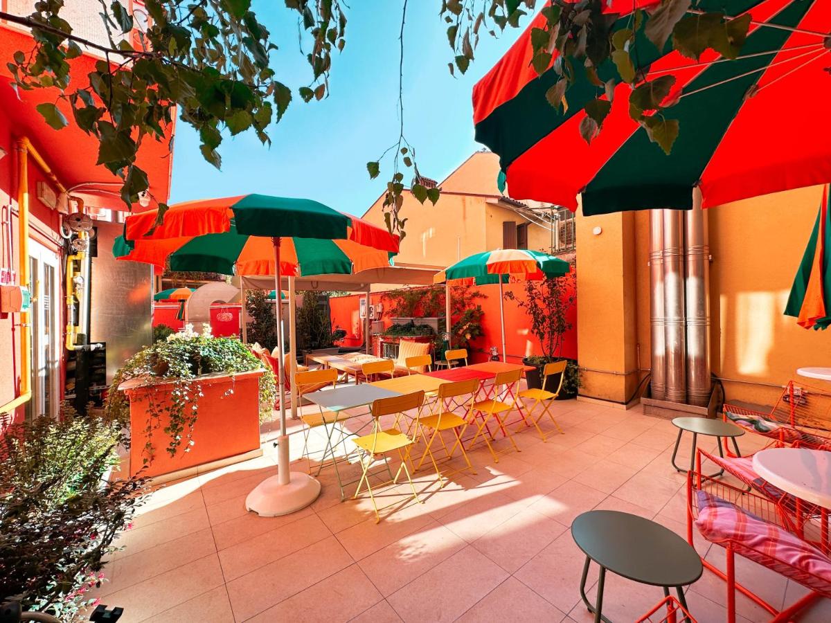 een terras met tafels, stoelen en parasols bij Ostello Bello Bologna in Bologna