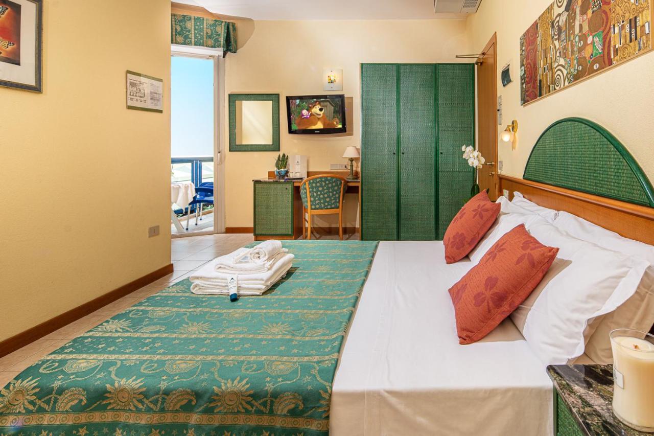 een slaapkamer met een bed met een groen hoofdeinde bij Hotel Bellevue in Bibione