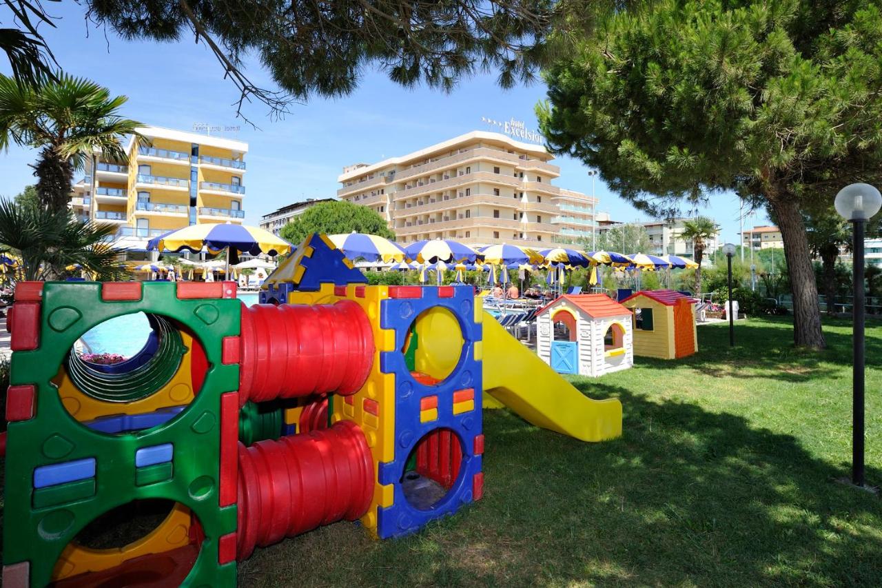 een speeltuin in een park met speeltoestellen en parasols bij Hotel Bellevue in Bibione