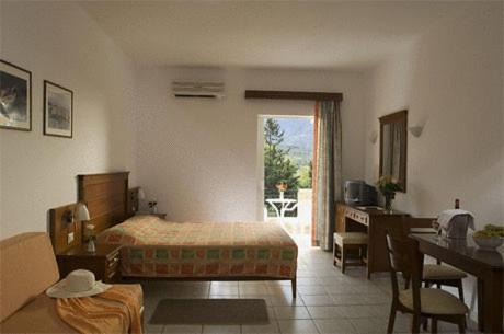 een slaapkamer met een bed, een tafel en een bureau bij Vardis Olive Garden in Georgioupolis