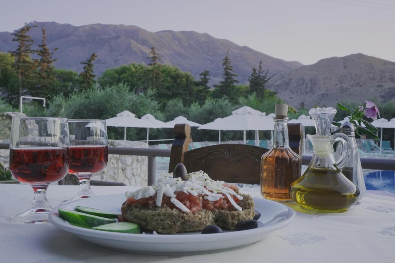Een bord met eten op tafel, met twee glazen wijn erbij. bij Vardis Olive Garden in Georgioupolis