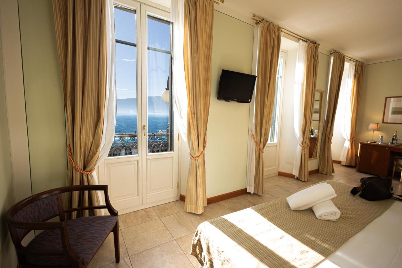 een slaapkamer met een bed en een groot raam bij LVG Hotel Collection - Belvedere San Gottardo in Verbania