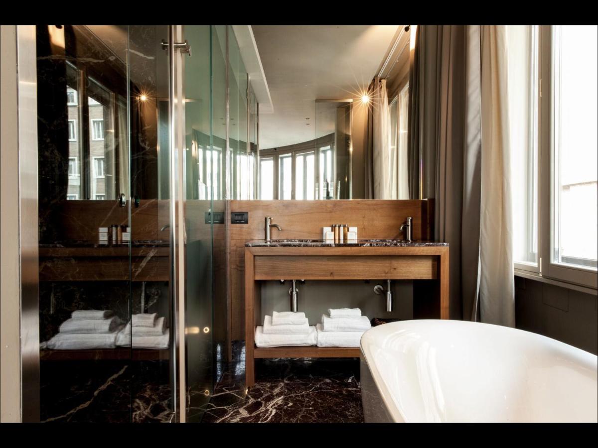 een badkamer met een wastafel, een spiegel en een badkuip bij Triviho Hotel in Rome
